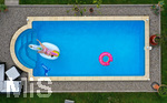 26.06.2020, Trend in der Corona-Pandemie: Der eigene Swimmingpool im Garten sorgt im Sommer fr Erfrischung wenn die Freibder geschlossen haben. Luftaufnahme eines Gartenpools im Unterallgu. Teenager schwimmt im Wasser auf einem Gummi-Einhorn. (Modelreleased)   