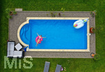 26.06.2020, Trend in der Corona-Pandemie: Der eigene Swimmingpool im Garten sorgt im Sommer fr Erfrischung wenn die Freibder geschlossen haben. Luftaufnahme eines Gartenpools im Unterallgu. Teenager sonnt sich auf einem Schwimmreifen im Wasser. (Modelreleased)  