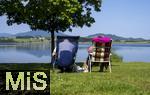 04.05.2023, Hopfensee in Bayern, Der Hopfensee bei Fssen im Allgu, Urlauber sitzen am See auf ihren Campingsthlen und geniessen die Aussicht.