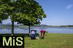 04.05.2023, Hopfensee in Bayern, Der Hopfensee bei Fssen im Allgu, Urlauber sitzen am See auf ihren Campingsthlen und geniessen die Aussicht.