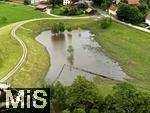 02.06.2024, Kirchheim bei Bad Wrishofen im Unterallgu, Nach dem Hochwasser nach andauernden Regenfllen ist das Wasser ber Nacht zgig abgelaufen. Hier in dem berlaufbecken fr eine Jahrhunderflut vor dem Dorf steht nur noch wenig Stauwasser, Tags zuvor ist der Damm ungeplant bergelaufen und hat den Kirchdorfern teils katastrophale Wasserschden beschert. Luftbild mit Drohne