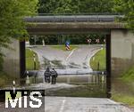 02.06.2024, Bad Woerishofen im Unterallgaeu, Hochwasser nach andauernden Regenfaellen, in der Unterfuehrung der Autobahn A96 zum Skylinepark bei Kirchdorf steht einen Tag nach dem Hochwasser noch der Grundwasserspiegel,  zwei Radfahrer fahren unerschrocken durch die Fluten, 
