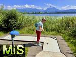 31.07.2023, Hopfensee in Bayern, Der Hopfensee bei Fssen im Allgu,  Minigiolfanlage direkt am See. Frau spielt Minigolf.