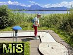 31.07.2023, Hopfensee in Bayern, Der Hopfensee bei Fssen im Allgu,  Minigiolfanlage direkt am See. Frau spielt Minigolf.