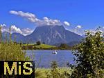 31.07.2023, Hopfensee in Bayern, Der Hopfensee bei Fssen im Allgu,  Um den Gipfel des Suling wabern noch tiefe Wolken. Auf dem See ein Tretboot in Schwanenform.