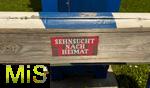 31.07.2023, Hopfensee in Bayern, Der Hopfensee bei Fssen im Allgu,  Auf einer Bank am Maibaum im Park steht ein Schild: Sehnsucht nach Heimat.