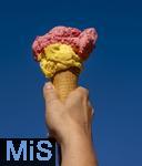07.08.2024, Eistte mit Mango- und Himbeer-Eis aus einer Bad Wrishofener Eisdiele. Eine Frau streckt ihre Eistte in den blauen Himmel.