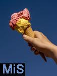 07.08.2024, Eistte mit Mango- und Himbeer-Eis aus einer Bad Wrishofener Eisdiele. Eine Frau streckt ihre Eistte in den blauen Himmel.