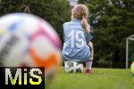 07.08.2024, Mdchen an den Ball, Pressekonferenz zur Kooperation mit dem FC Bayern Mnchen, am Vereinsgelnde FT Gern Mnchen,   Ein teilnehmdes Mdchen sitzt in einer Pause auf dem Ball auf dem Sportplatz. 