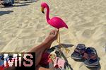 23.07.2025,  Beliebtes Reiseziel der Deutschen, Mallorca. Hier Cala Ratjada am Strand Cala Agulla. Eine pinke Flamingofigur steckt im Sand. Eine Urlaubergruppe aus Deutschland hat diese Spassfigur zum Scherz als Malle-Maskottchen mitgebracht. 