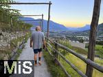 31.07.2025, Meran in Sdtirol, Italien. Ortsteil Algund, Ein Mann spaziert den Waalweg entlang, am Hang eines Weinberges.