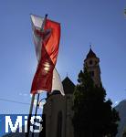 31.07.2025, Meran in Sdtirol, Italien. Ortsteil Dorf Tirol,  Landesflagge von Sdtirol weht an der Kirche. Die Landesflagge von Sdtirol mit dem Sdtiroler Wappen in der Mitte zeigt einen doppelkpfigen, schwarzen Adler auf goldenem Grund, der auch als Wenzeladler bekannt ist, und einen roten Adler auf weiem Grund, der das Tiroler Wappen darstellt. Die Flagge ist ein Symbol fr die Autonomie und Identitt Sdtirols innerhalb Italiens. Pfarrkirche Hl. Johannes der Tufer