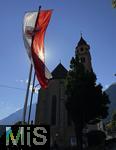 31.07.2025, Meran in Sdtirol, Italien. Ortsteil Dorf Tirol,  Landesflagge von Sdtirol weht an der Kirche. Die Landesflagge von Sdtirol mit dem Sdtiroler Wappen in der Mitte zeigt einen doppelkpfigen, schwarzen Adler auf goldenem Grund, der auch als Wenzeladler bekannt ist, und einen roten Adler auf weiem Grund, der das Tiroler Wappen darstellt. Die Flagge ist ein Symbol fr die Autonomie und Identitt Sdtirols innerhalb Italiens. Pfarrkirche Hl. Johannes der Tufer